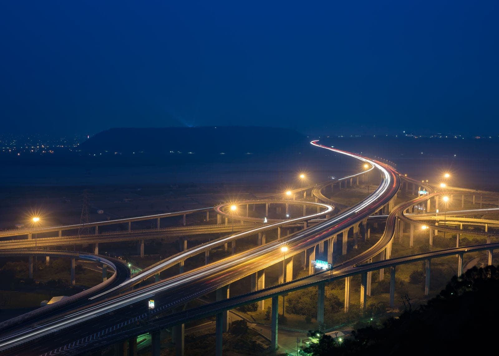 A lit highway interchange at dusk seen from above
