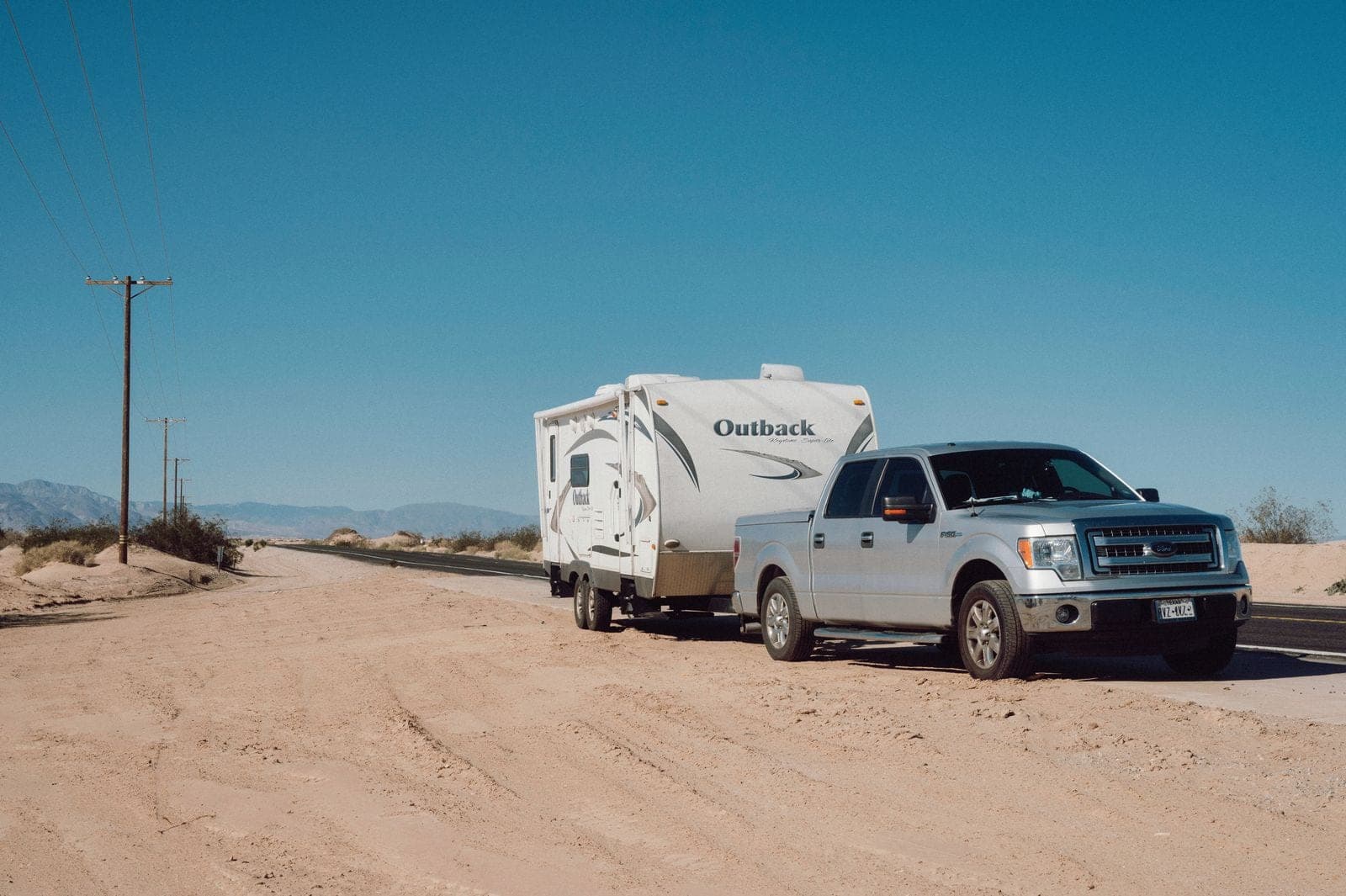 A pickup truck towing a travel trailer on an open road